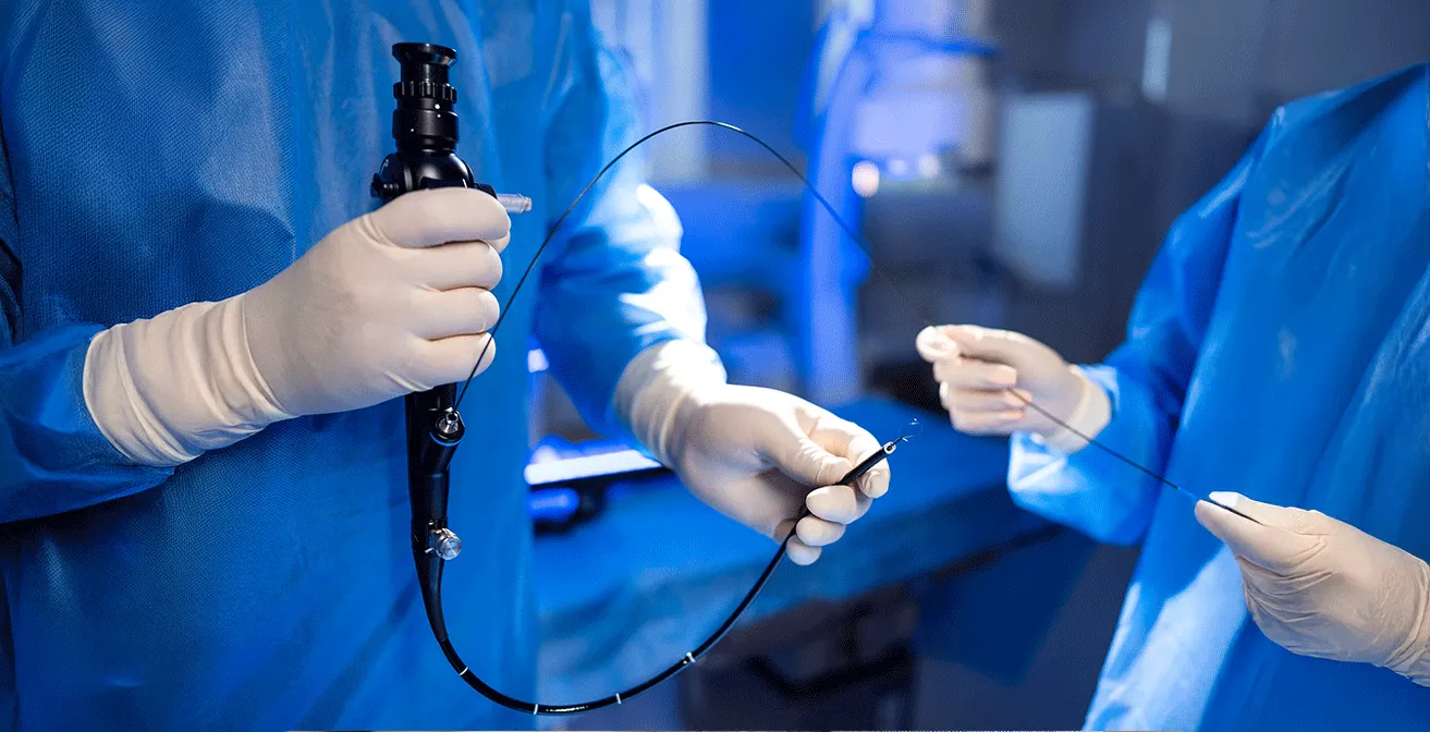 Medical team performing an endoscopy procedure, with two healthcare professionals in scrubs and gloves using an endoscope on a patient.